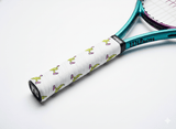 White custom tennis overgrip printed with a cartoon banana pattern on a teal Wilson racket handle.