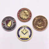 Four custom challenge coins in antique silver, antique bronze, and gold finishes with raised metal detail and enamel color