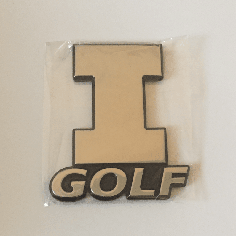 Chrome 3D car emblem of the Illinois block "I" with "Golf" lettering, shown in its packaging.